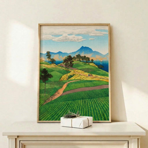 Vintage-style Japanese art print showing a tranquil coastal mountain landscape in emerald green and sky blue tones, featuring terraced fields, trees, and a sailboat on calm waters.
