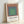 Modern minimalist wall art displaying layered squares in soft sage green, light green, cream, and slate blue on a neutral background.