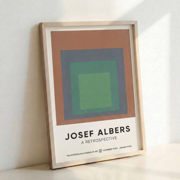 Modern minimalist wall art displaying layered squares in soft sage green, light green, cream, and slate blue on a neutral background.
