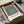 Framed geometric poster with nested color squares in warm terracotta and cool slate blue balanced with sage and cream tones.
