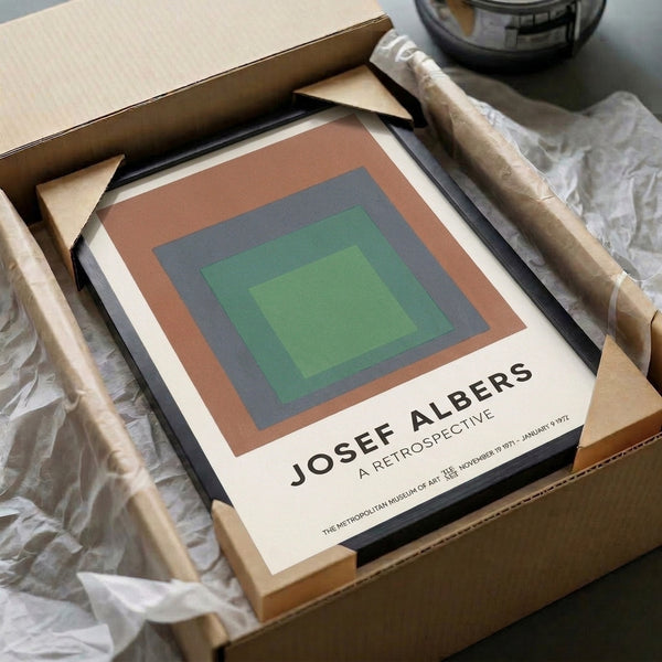 Framed geometric poster with nested color squares in warm terracotta and cool slate blue balanced with sage and cream tones.