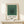 Geometric wall art displaying centered nested squares in cream, sage green, forest green, and charcoal—a serene exploration of form and color balance.