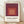 Framed minimalist poster featuring nested squares in warm tones of maroon, coral, and cream, exemplifying Bauhaus color theory and geometric abstraction.