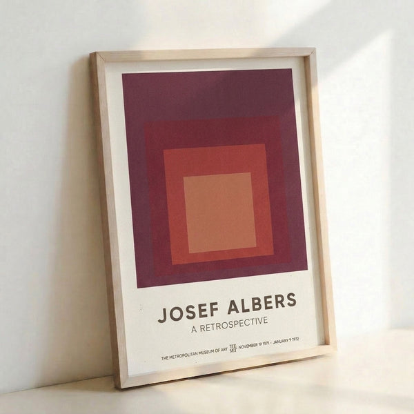 Structured geometric poster displaying layered squares in maroon, coral, and cream, reflecting the systematic color exploration central to Albers' artistic practice.