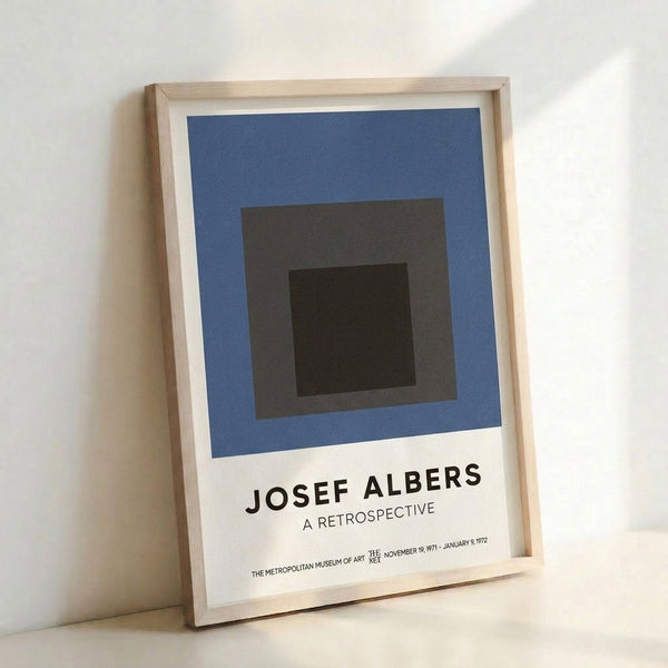 Refined geometric poster displaying layered squares in muted charcoal, slate blue, and dark brown, embodying Bauhaus aesthetic on a cream background.