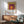 Nested squares in a warm palette of plum, orange, gold, and burgundy form a serene, geometric composition inspired by modernist color theory and displayed as framed wall art.