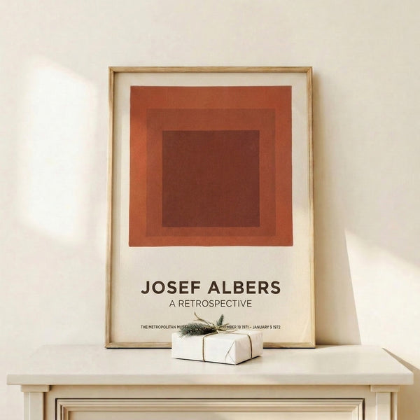 Minimalist framed artwork with nested square shapes in burnt sienna and cream tones, evoking the meditative simplicity of mid-century abstract design.