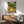 Joyful tropical wall art depicting a curious lion cub interacting with a monkey, parrot, and turtle in a dense, whimsical garden of flowering plants and verdant leaves in boho aesthetics.