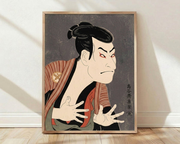 Framed Japanese woodblock portrait of a kabuki actor in traditional theatrical costume with dramatic makeup, rendered in bold black lines and deep rust red, cream, and gold tones.