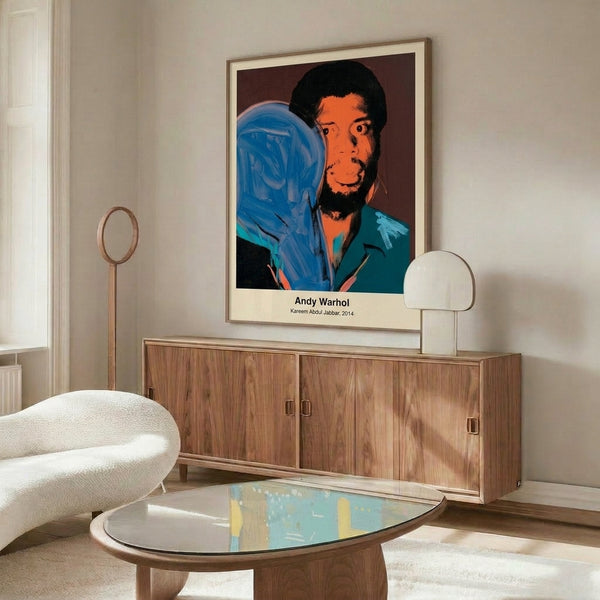 Framed pop art artwork of Kareem Abdul-Jabbar rendered in bold yellow, vibrant magenta, and electric blue hues with graphic modern styling.