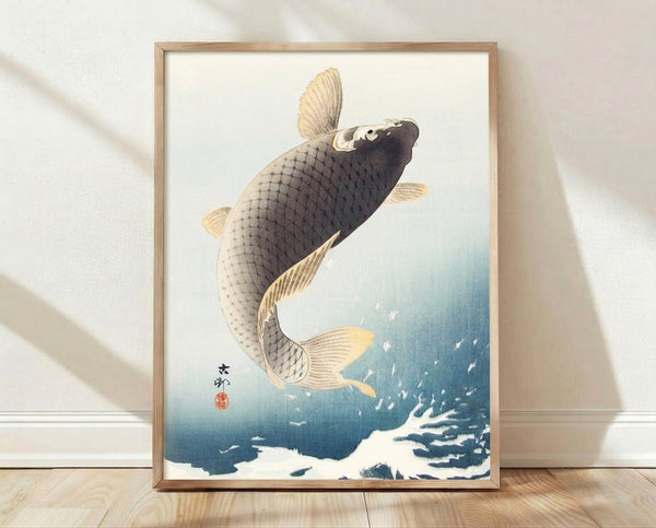 Framed Japanese woodblock print of a dynamic leaping koi fish in cream, pale blue, and gold tones against a serene aquatic background.