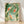 Three koi fish swimming among aquatic plants in a serene Japanese woodblock-style painting with sage green, cream, rust, and black tones.