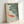 Framed zen wall art depicting graceful koi in water with floating lily pads, executed in soft blue-gray and sage green with coral accents in a minimalist Japanese style.