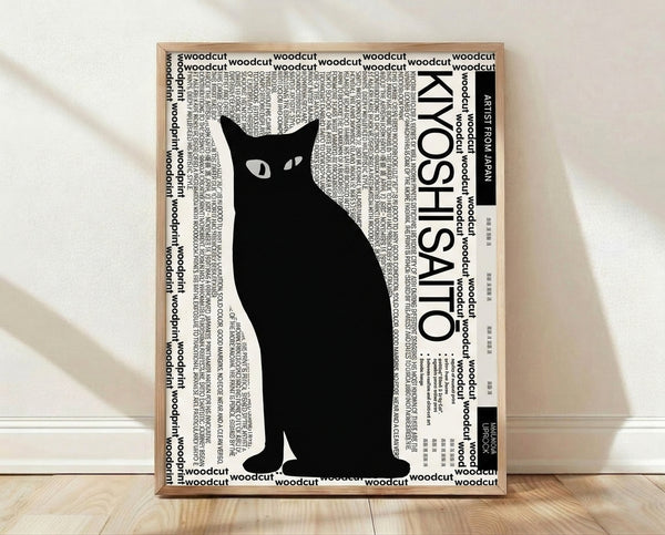 Minimalist black and white woodcut print of a cat with clean, flowing lines and graphic elegance, displayed as a framed poster on a wall.