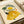 Botanical watercolor portrait of a faceless woman with citrus and pear motifs, layered with palm and decorative leaves in a cheerful cream, yellow, and green palette.