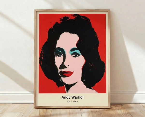 Pop art portrait with a woman's face in vibrant magenta, cyan, and yellow tones against a black and white background, displayed as a framed print on a wall.