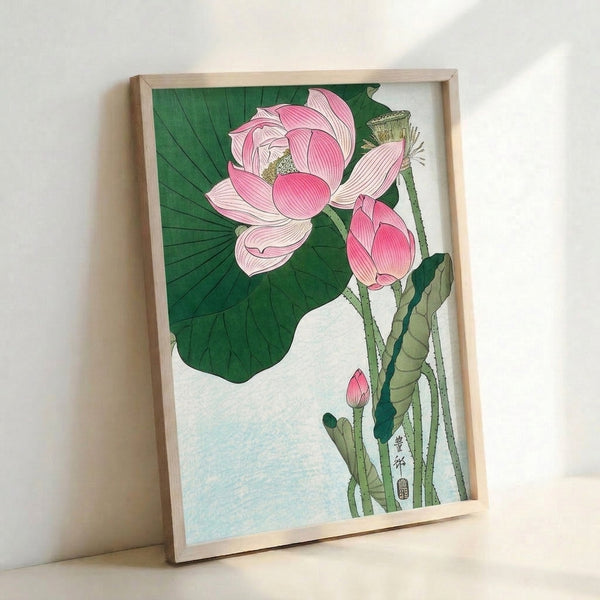 Framed poster depicting a graceful lotus flower in soft pink tones surrounded by green foliage, created in the style of Japanese woodblock art with delicate line details and cream background.