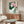 Framed wall art featuring a serene pink lotus blossom amid green stems and foliage, created in Japanese woodblock line art style with warm cream and gold tones.