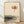 Minimalist watercolor framed poster of a solitary lotus flower floating on rippling water in warm coral and burnt orange tones against a cream background, evoking serene Japandi aesthetics.