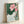 Contemplative Japanese woodblock artwork showcasing a blooming lotus amid flowing stems and leaves in a harmonious palette of dusty pink, cream, and forest green.