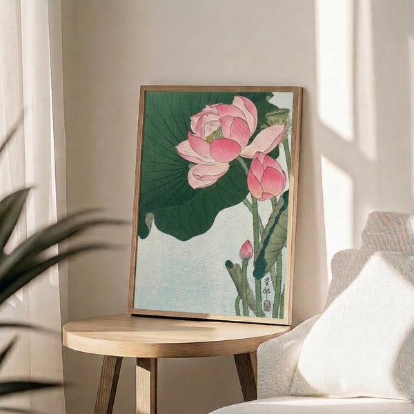 Traditional Japanese-style woodblock print of a serene lotus blossom surrounded by organic stems and foliage in dusty pink, cream, and soft golden tones, framed for wall display.