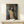 Framed expressionist artwork featuring a mysterious faceless silhouette crowned with a radiant halo, composed in warm and cool contrasting tones.