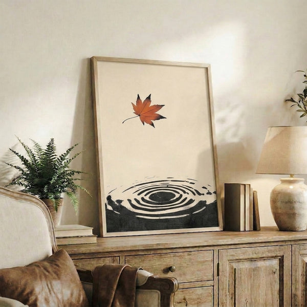 Minimalist autumn-themed poster combining Japanese line art aesthetics—a maple leaf suspended in a ripple pattern and enso circle, executed in warm rust-orange and black on cream for meditative spaces.