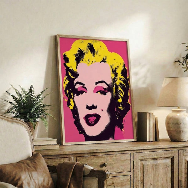 Modern pop art-inspired portrait featuring simplified facial features in striking pink, blue, and yellow palette, framed and displayed on a wall.