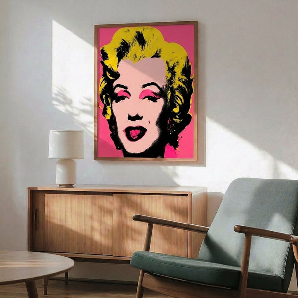 Contemporary pop art print depicting a stylized face in bright layered colors including hot pink and electric blue tones, framed on a wall.