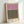 Minimalist abstract poster displaying layered rectangles in soft mauve pink and olive green tones with warm burnt orange highlight against neutral backdrop.