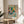 Framed Matisse-style print of a girl in a richly colored domestic interior with furniture, plants, and still-life elements in emerald green, coral red, and soft pastel tones.