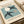 Framed contemporary art featuring cut-paper bird and lunar motif in muted dusty blue, cream, and charcoal with elegant compositional balance.