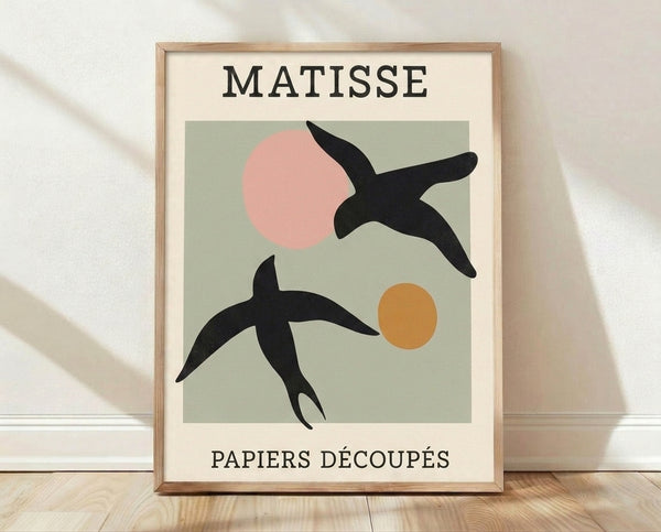 Framed abstract bird art print in Matisse style featuring sage green, blush pink, and ochre cut-out shapes with playful minimalist composition on cream background.