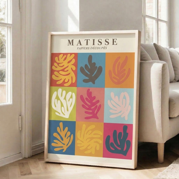 Framed wall art displaying a cheerful grid layout of papier découpé-inspired shapes in vibrant coral, golden yellow, and blue hues, evoking botanical forms with playful modernist flair.