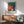 Matisse's The Music print displaying a sensual figure with guitar nestled among vibrant plants in cream, coral, and emerald hues on gallery wall.