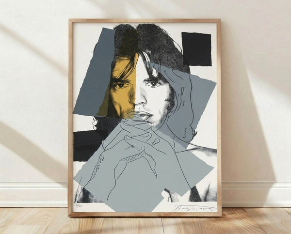 Pop art portrait of Mick Jagger with bold, contrasting colors and graphic silkscreen effect, framed poster on wall.