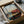 Retro Americana poster featuring a solitary diner booth with coffee cup, gazing out toward a highway disappearing into a desert sunset landscape in muted mid-century palette of red, gray, and cream.