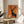 Serene woodland scene depicting a parent deer and young fawn in profile, modern silhouette art in warm burnt orange and deep charcoal tones on a cream background.