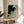 Contemplative bird wall art in mid-century style showing a yellow warbler resting on dark wing-like branches against muted teal and cream, displayed as a framed poster.