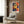 Modern wall art poster capturing the warmth and vitality of mimosa flowers through abstract paper cutout shapes in vivid reds, oranges, yellows, and blues with striking black surrounds.