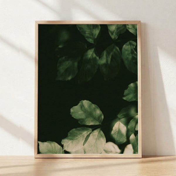 Framed minimalist botanical print featuring dark green leaves on a cream background, creating a serene Japandi-inspired wall art piece.