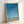 Calm ocean-inspired wall art in modern minimalist style depicting a peaceful beach with a bird, pole, and trash can against soft blue and beige hues.