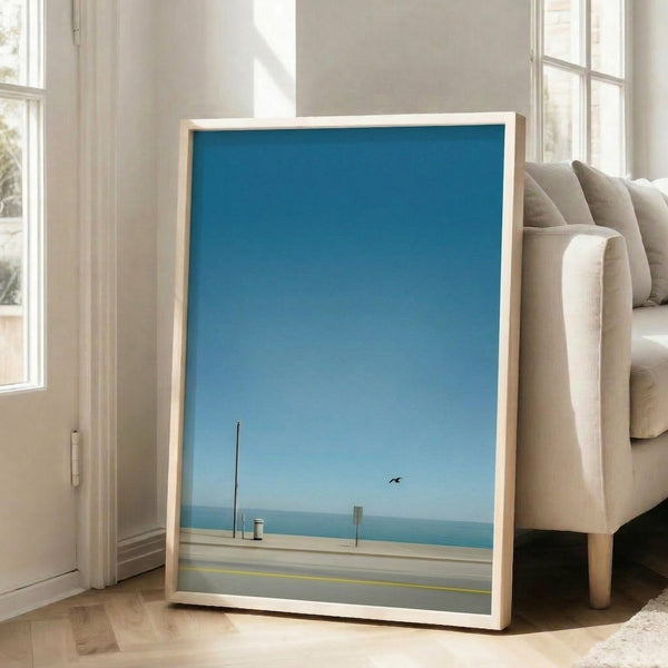 Japandi-style framed poster of a tranquil coastal landscape with simplified forms, featuring a bird and beach elements in soothing teal and grey tones.