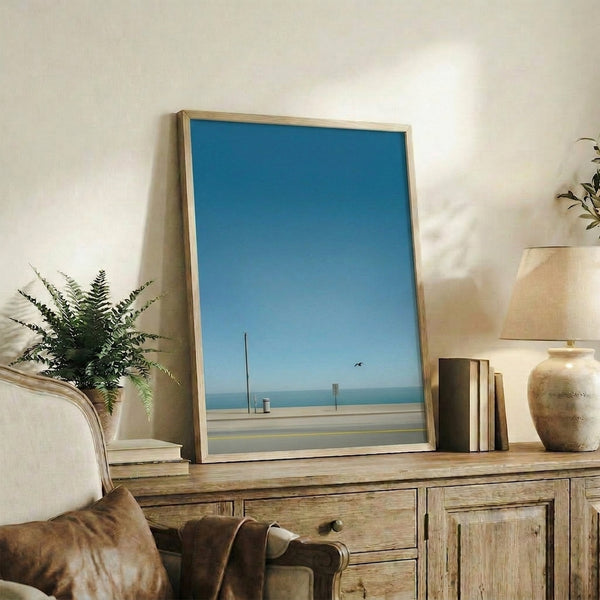 Wabi sabi art print capturing serene beachside beauty with minimal details—a bird, utility structures, and ocean horizon in soft, understated colors.