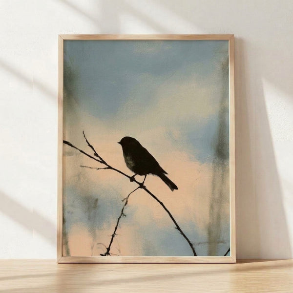 Minimalist watercolor art print showing a black bird silhouette perched on a branch against a pale blue and cream sky, framed on a wall.