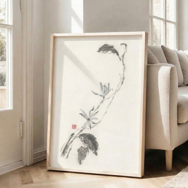 Framed zen-inspired botanical print showing a graceful lotus branch in soft charcoal and black ink strokes against cream, embodying peaceful minimalist aesthetics.