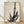 Minimalist sumi-e ink wash painting of a bamboo stalk with delicate leaves and a small lizard, rendered in black and gray on white, framed on a wall.