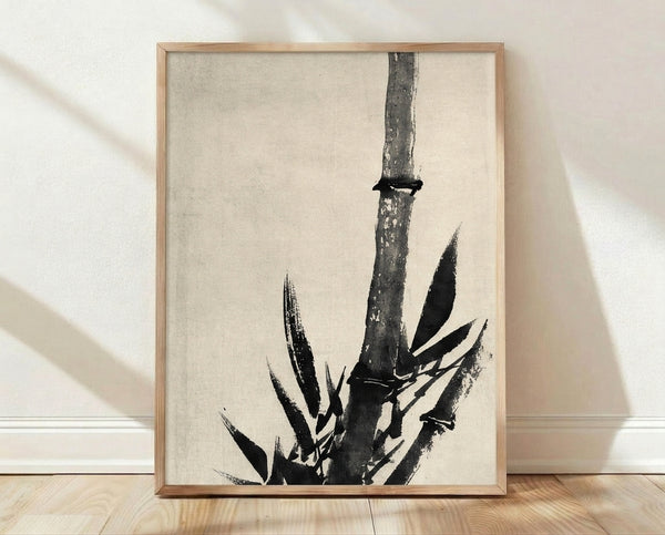 Minimalist sumi-e ink wash painting of a bamboo stalk with delicate leaves and a small lizard, rendered in black and gray on white, framed on a wall.