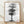 Minimalist watercolor painting of a solitary tree with delicate branches rendered in charcoal and black ink wash against a soft white and gray background, evoking a contemplative, serene mood.