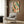 Framed abstract wall art combining black lines and organic shapes in orange, teal green, and cream, depicting a thoughtful, minimalist interpretation of a busy street market or library scene.